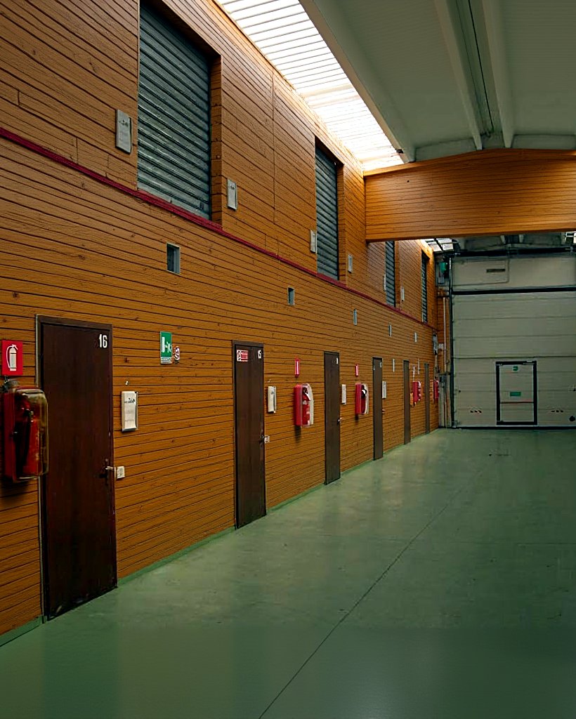 Corridoio del capannone con i box deposito: porte numerate, serrande e uscite di sicurezza